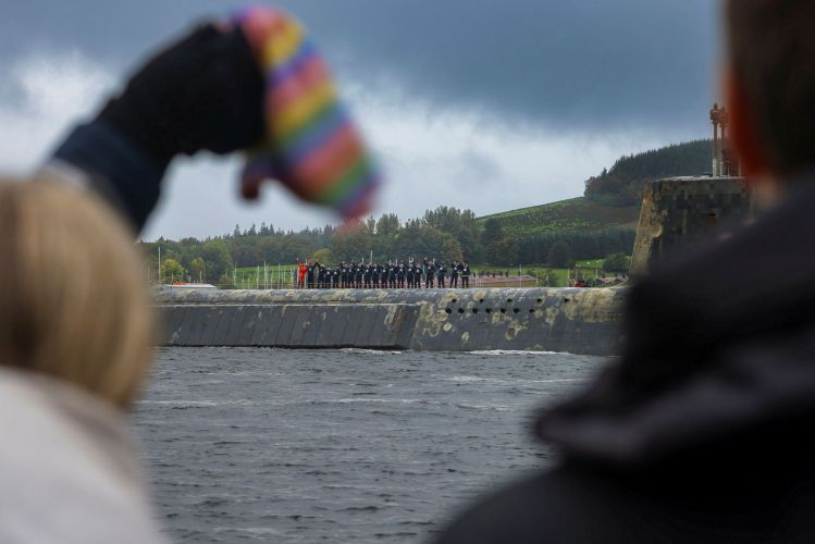 Submariners aboard the Vanguard Class submarine wave to loved ones as she comes in to dock