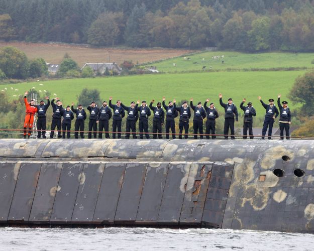Submariners aboard the Vanguard Class submarine wave to loved ones as she comes in to dock