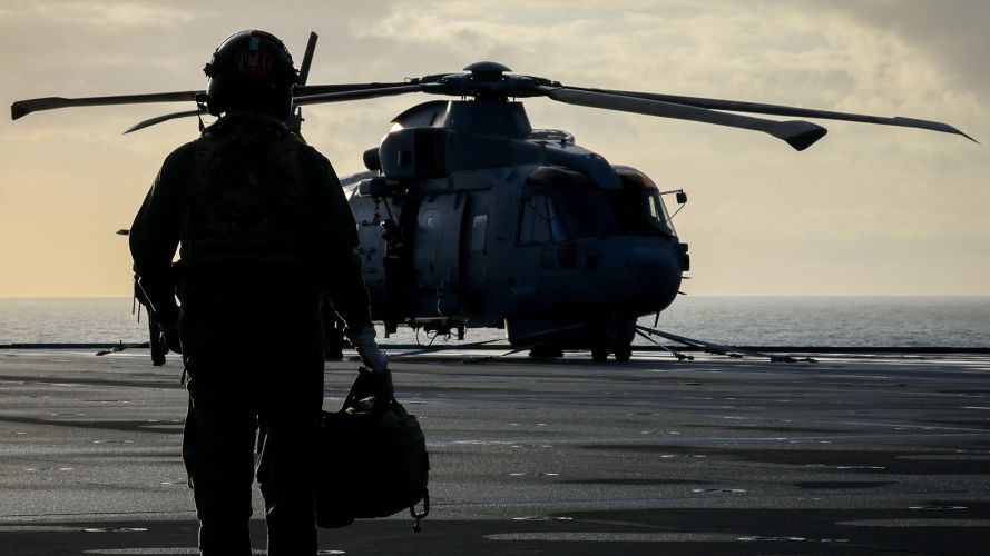 A crew member from 814 Naval Air Squadron walks out to their Merlin Mk2 on board HMS Prince of Wales during Operation Firecrest in the High North