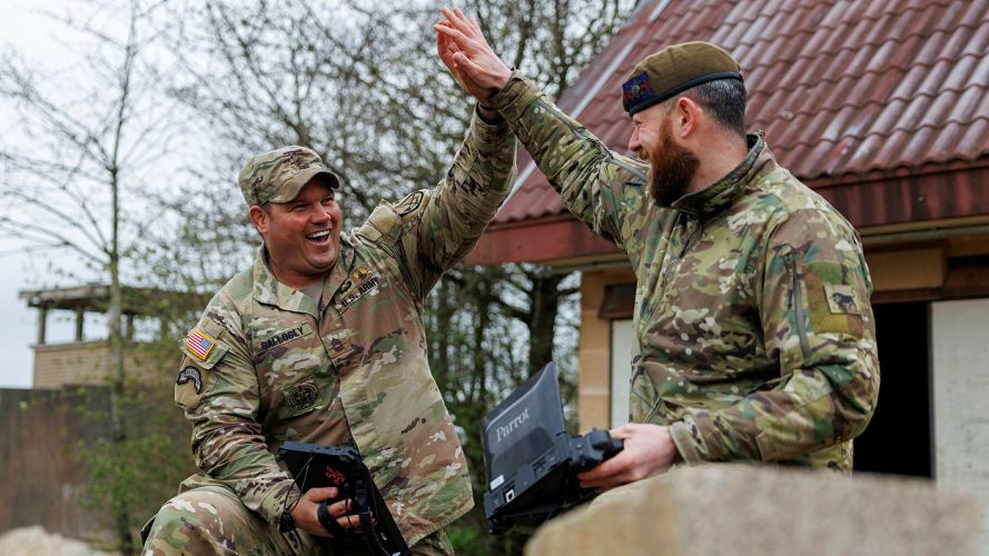 US and British soldiers share a high five during the Army War Fighting Experiment - a British Army initiative to further the development of drone swarms and the instantaneous transfer of data