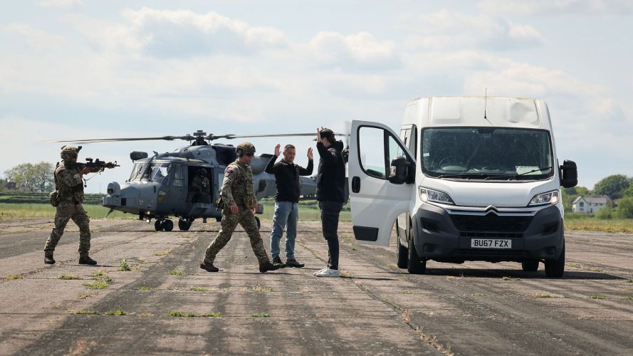 The commando to the rear provides covering arcs, while the other proceeds to detain and secure the individual