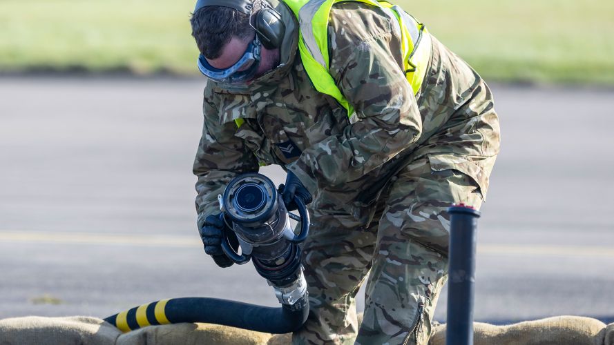 A member of the ground crew deployed to Leuchars Station from RAF Wittering prepares to attach a fuel line to a Typhoon as the jet keeps its engines running - process known as hot pit refuelling