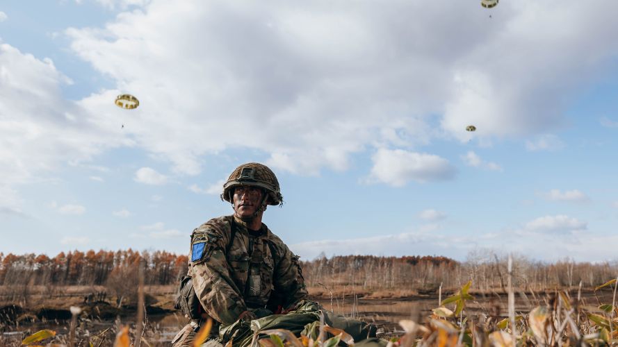 A Para sits as Paras parachute down to the ground 