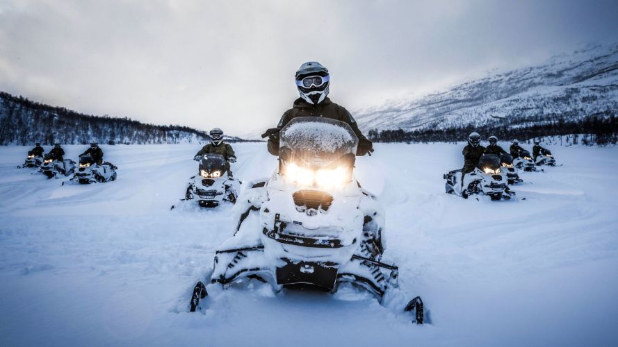 Royal Marines cross a frozen lake on snowmobiles during a deployment to Norway 