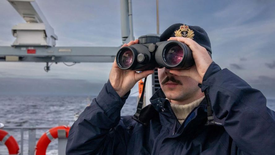 A sailor looks out into the open water through his binoculars (Picture: Royal Navy)