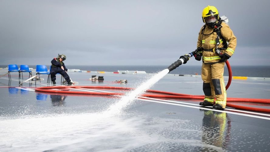 A firefighter hoses down the deck before the medical team can treat the casualty (Picture: MOD) HMS Queen Elizabeth crash-on-deck exercise