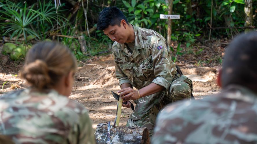 A member of personnel shows personnel how to make a fire in the jungle