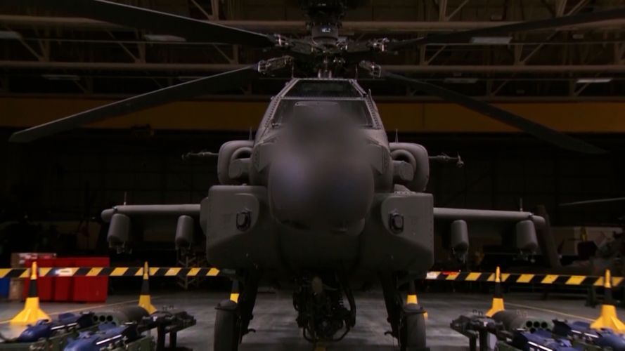 A front on view of a stationary Apache AH-64E helicopter.