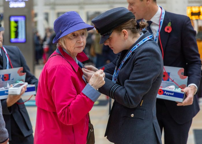A member of the Armed Forces helps pin a poppy onto a member of the public while fundraising for London Poppy Appeal 