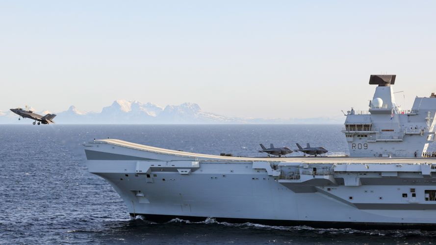 Aerial image of HMS Prince of Wales with Fjord in the background as a F35-B Lighting Jet takes off 03032024 CREDIT MOD