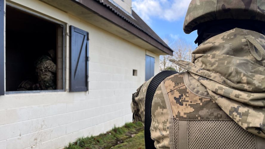 An over the shoulder close up of Ukrainian volunteers in a fake village in the UK for frontline training.