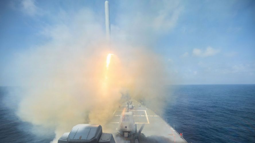 Elsewhere, the Arleigh Burke-class guided-missile destroyer USS Spruance fires a  Tomahawk land attack missile 