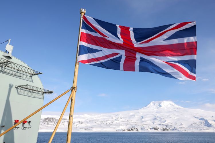 British flag flies on HMS Prince of Wales with island of Jan Mayen in the background 130422 CREDIT Royal Navy