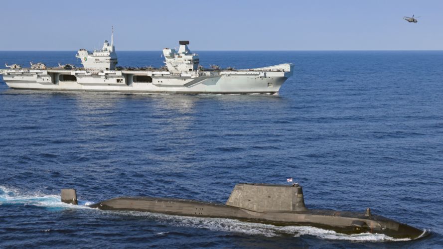 HMS Queen Elizabeth (background) with an Astute Class submarine and Merlin helicopter on Carrier Strike Group 21 deployment (Picture: MOD).