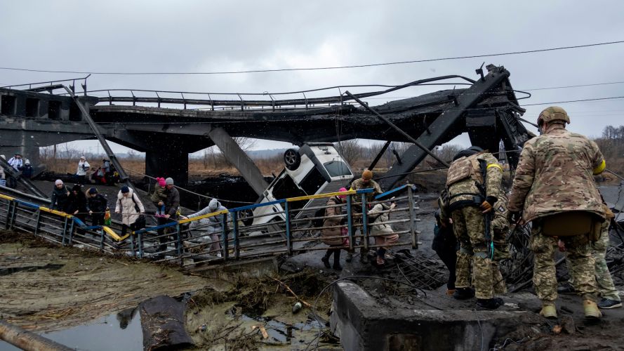 Ukrainian troops help civilians cross the shelled bridge connecting the town of Irpin and Kiev