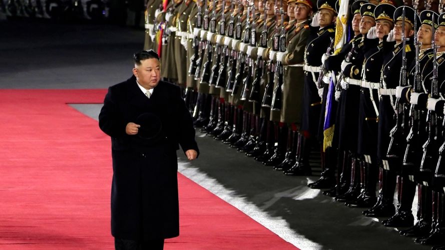 KIM JONG UN HOLDING HIS HAT AND WALKING WHILE MILITARY OFFICERS SALUTE DURING MILITARY PARADE