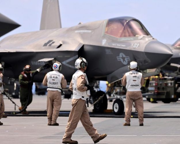 Members of VFMA-211 prepare an F35B Lightning Jet for a launch from HMS Queen Elizabeth as the Carrier Strike Group joins the fight against