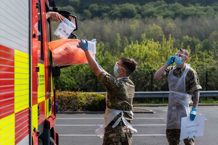 Patient drops off completed self test CORONAVIURS COVID19 kit into the collection box during the Mobile Testing Unit at Scarborough