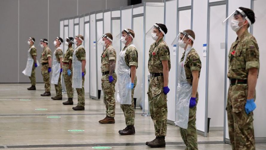 Personnel helping with the mass covid testing on Merseyside stand during a two minute silence at the Arena Convention Centre in Liverpool to remember the war dead (Picture: PA).