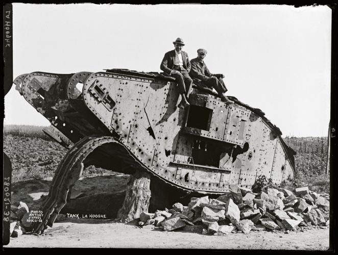 Two Belgian farmers sit on the wreck of the World War 1 British tank
