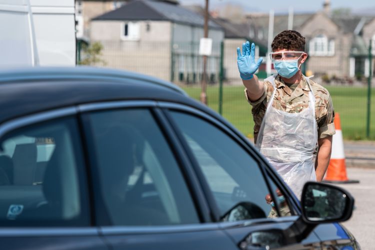 Soldier gestures for the driver to stop at the collection station during a drive through mobile testing unit at Kendal Leisure Centre COVID19 Coronavirus