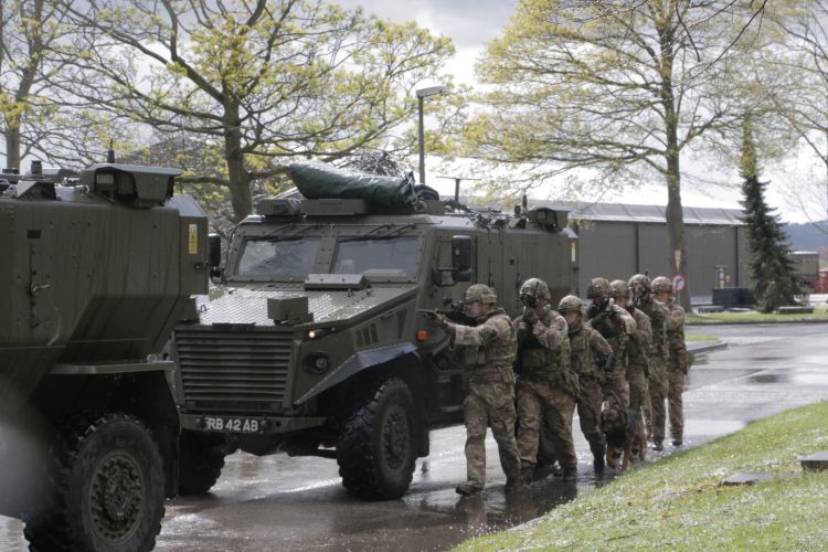 Soldiers alongside Foxhound vehicle during a demonstration.