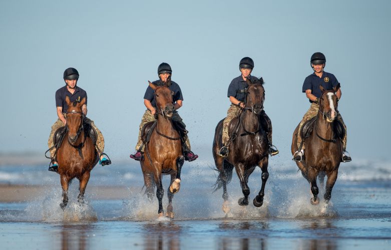 Soldiers and horses from The King's Troop Royal Horse Artillery exercise in the sea at Holkham in Norfolk