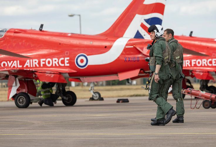 Two pilots walking alongside an RAF Red Arrow jet at RAF Scampton