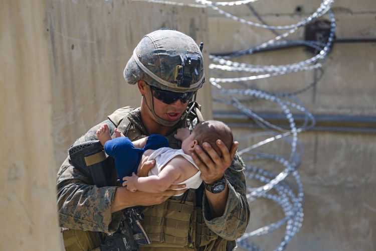 A US Marine comforts an infant while waiting for his mother during an evacuation at Kabul airport 