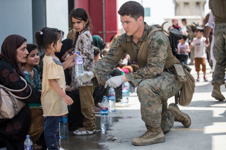An American Marine gives fresh water to a child