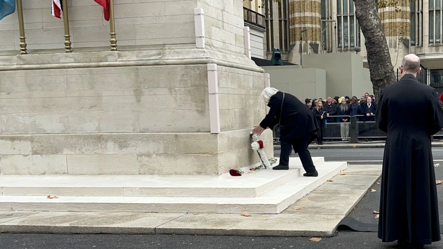 Widow laying a wreath in the shape of a cross made of white chrysanthemums 111024 CREDIT WAR WIDOWS ASSOCIATION