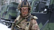 Corporal Reece Wilkinson-Wilson of 3 Rifles stands in front of a Finnish army Hägglund & Söner BV206 tracked utility vehicle during Exercise Northern Axe