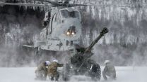 Personnel from 29 Commando Regiment Royal Artillery deployed in Norway shelter from downwash as they wait with a 105mm Light Gun to be lifted