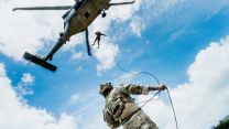 A US Navy explosive ordnance disposal technician secures a rope on the ground for a Peruvian navy counterpart descending from an SH-60 Sea Hawkat Bellows Air Force Station