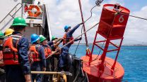 Personnel on board the US Coast Guard cutter Hollyhock place a new buoy off the coast of Honolulu as part of a restoration project to ensure the safety of sea lanes