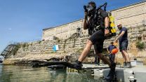 A member of the Royal Navy Diving and Threat Exploitation Group jumps into the water during a routine drill in Portland