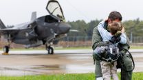An F-35B pilot from 617 Squadron gives his son a hug in the rain after flying back to RAF Marham at the end of Operation Highmast