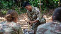 A member of personnel shows personnel how to make a fire in the jungle