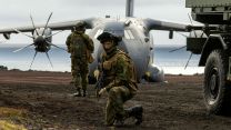 A Norwegian reservist escorts a Strikemaster vehicle with an RAF A400M Atlas in the background as the two nations train together during Operation Atlantic City on the remote island of Jan Mayen
