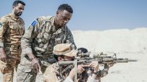A member of 16 Air Assualt Brigade training a Kuwaiti counterpart, aiming a weapon, on Exercise Desert Warrior 