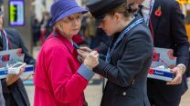 A member of the Armed Forces helps pin a poppy onto a member of the public while fundraising for London Poppy Appeal 