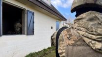 An over the shoulder close up of Ukrainian volunteers in a fake village in the UK for frontline training.