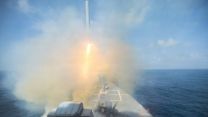 Elsewhere, the Arleigh Burke-class guided-missile destroyer USS Spruance fires a  Tomahawk land attack missile 