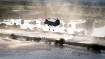 Chinook helicopter lowers bag of aggregates into the breach of a riverbank in an effort to stop the river Steeping causing further flooding to the local area CREDIT RAF
