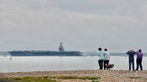 Locals watch the US Navy aircraft carrier, USS Gerald R Ford come into the Solent CREDIT Amy Savage, @AmyzJS13