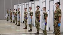 Personnel helping with the mass covid testing on Merseyside stand during a two minute silence at the Arena Convention Centre in Liverpool to remember the war dead (Picture: PA).