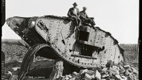 Two Belgian farmers sit on the wreck of the World War 1 British tank