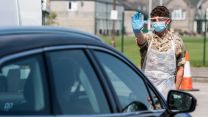 Soldier gestures for the driver to stop at the collection station during a drive through mobile testing unit at Kendal Leisure Centre COVID19 Coronavirus