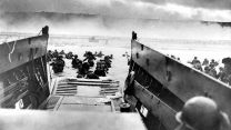 Troops wade ashore from a landing craft onto a Normandy beach