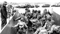 US Army troops disembark from a landing craft on a Normandy beach